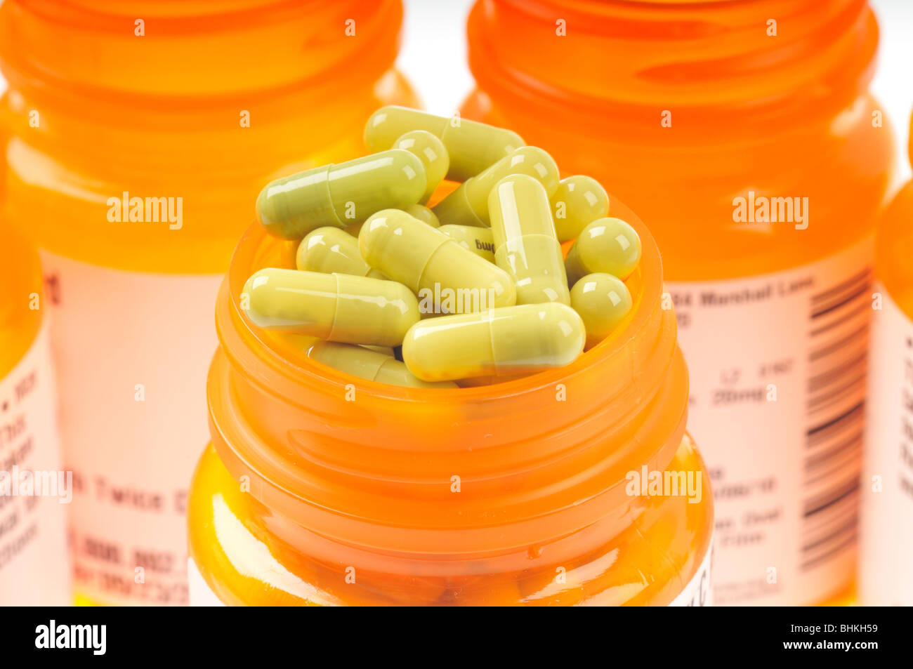 Prescription bottle filled with green capsules of  cymbalta surrounded by other prescription bottles on white background Stock Photo