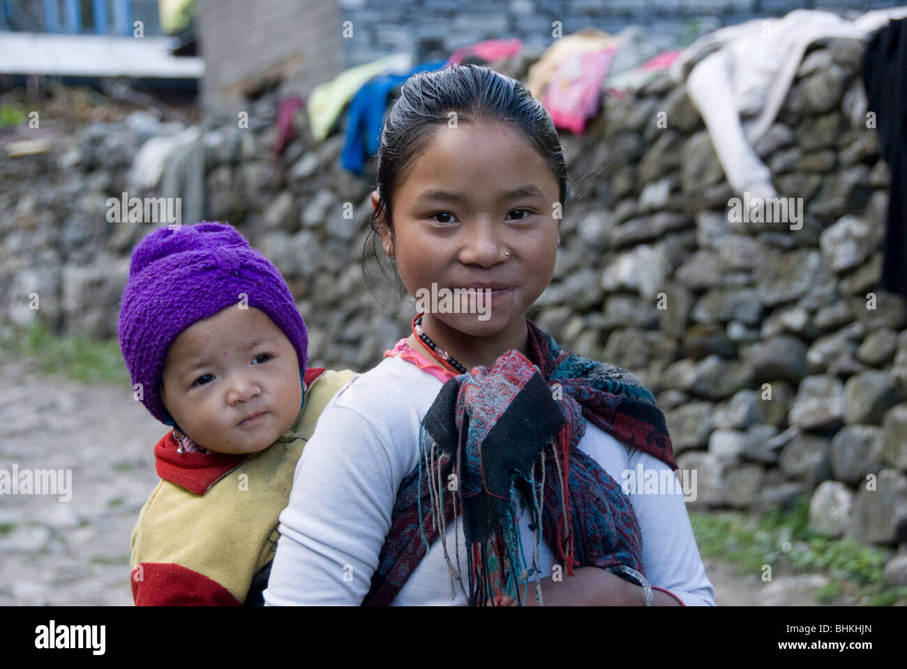 Young girl carrying sibling in street, near Bagarchhap, Annapurna ...