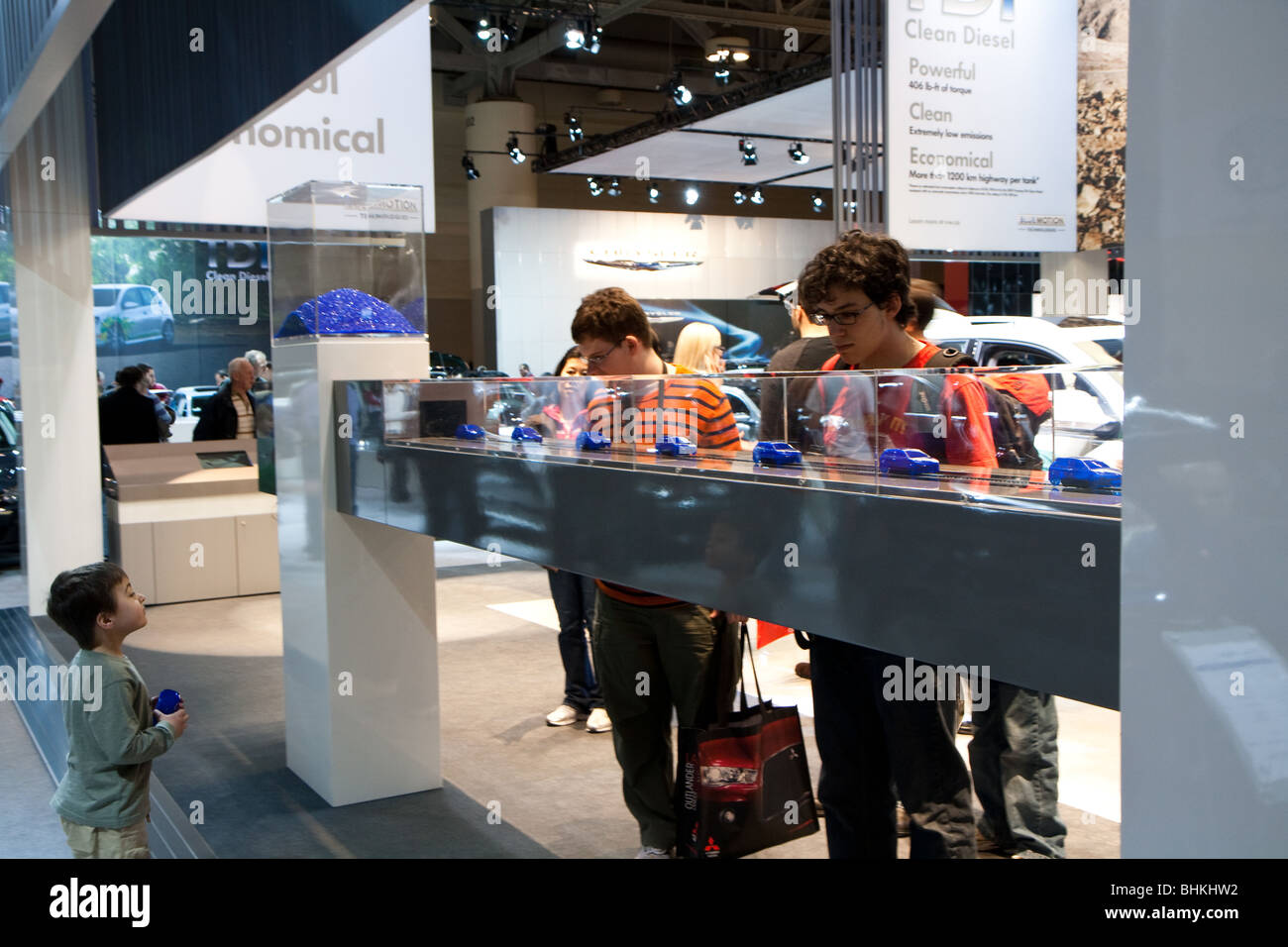 Children watching plastic toy cars to be produced in a assembly line at the Volkswagen VW autoshow booth Stock Photo