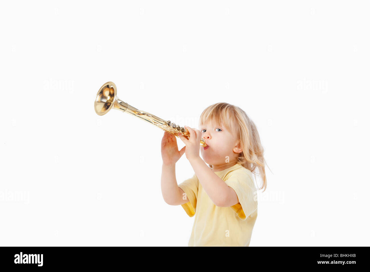 boy with long blond hair playing with toy trumpet Stock Photo