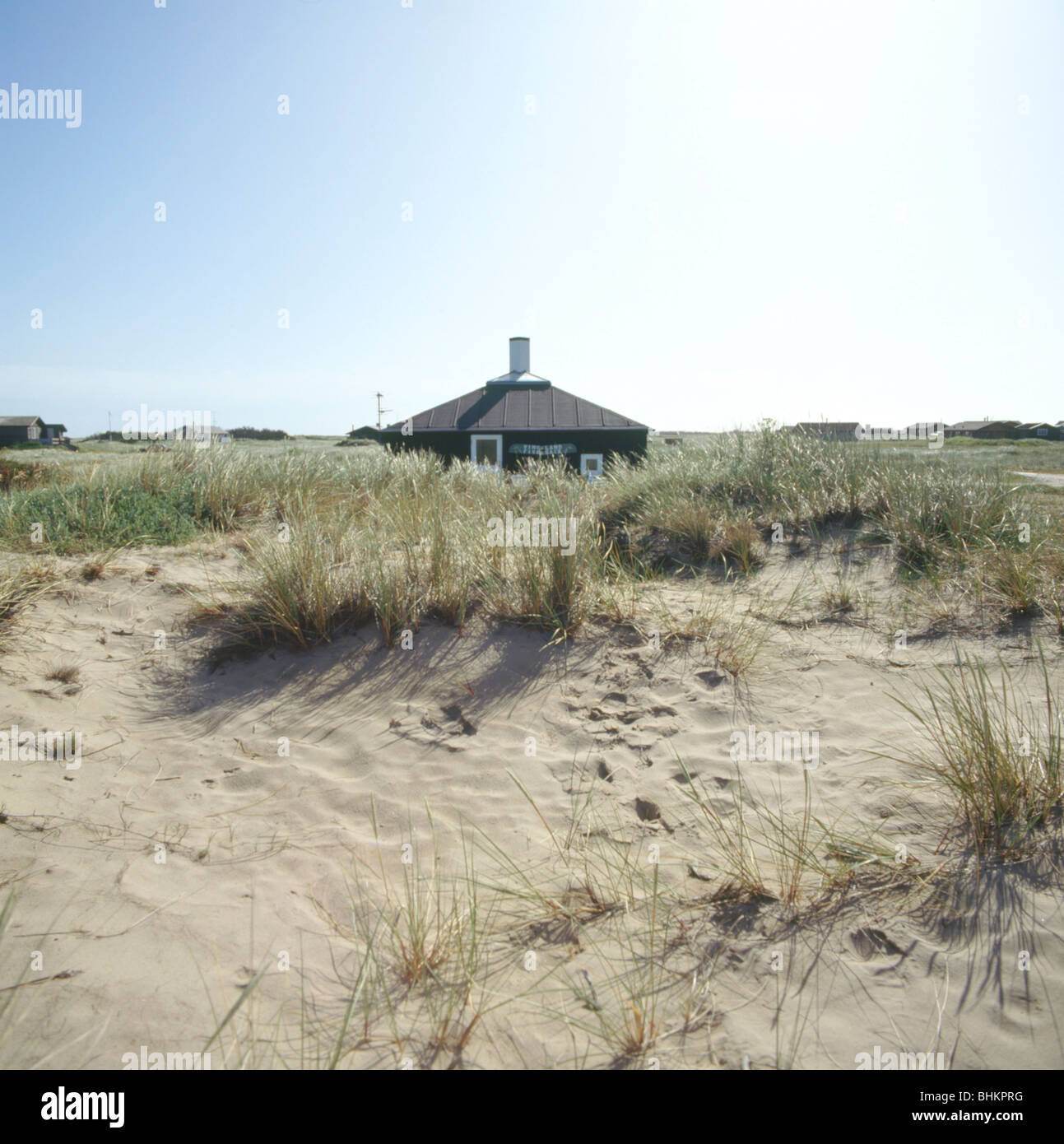 View across sand dunes of small single story beach house in Denmark ...