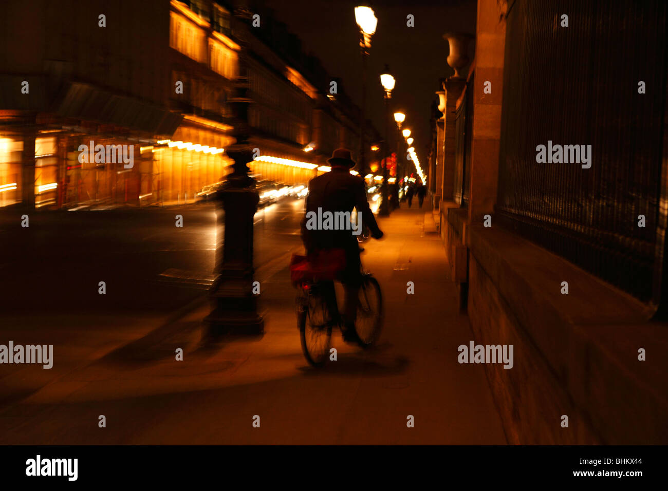 artsy image of a Paris commuter on a bicycle at night.  Panned motion photograph. Stock Photo