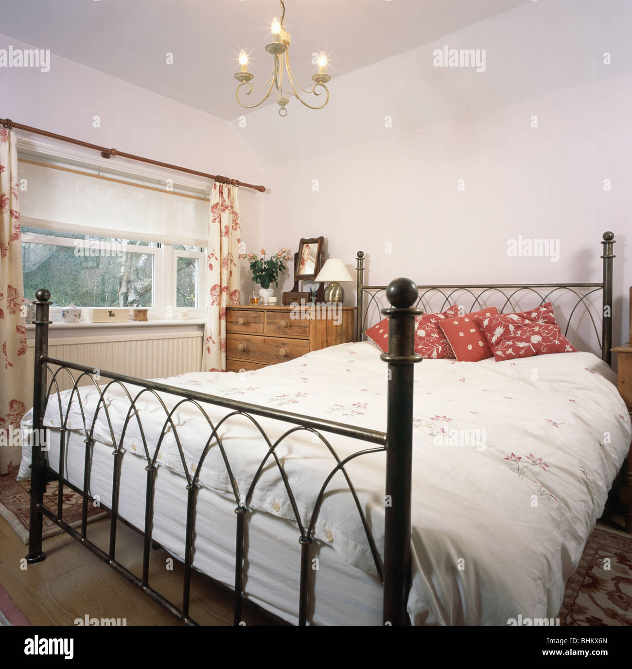 Black Cast Iron Bed With Red Cushions And White Bedlinen In