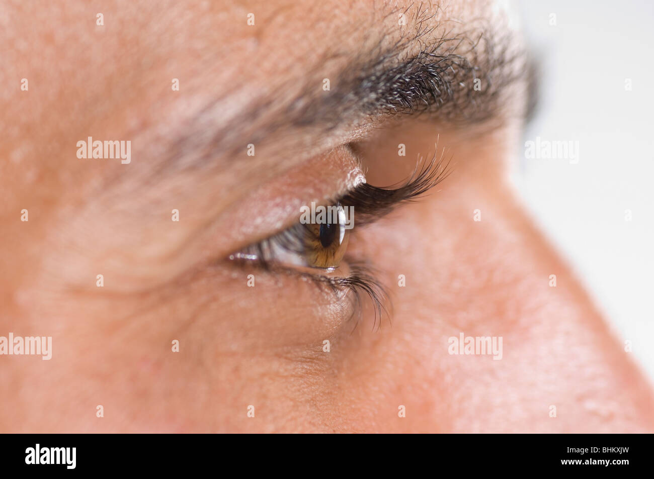 Close up of a young man's eye looking away against a white background