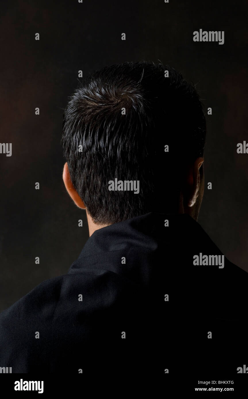 rear view portrait of a man standing in the dark Stock Photo
