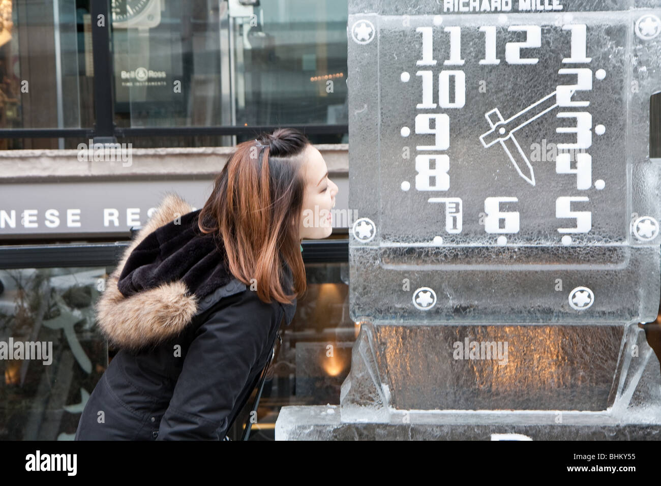 A girl eating a clock made up of ice Stock Photo