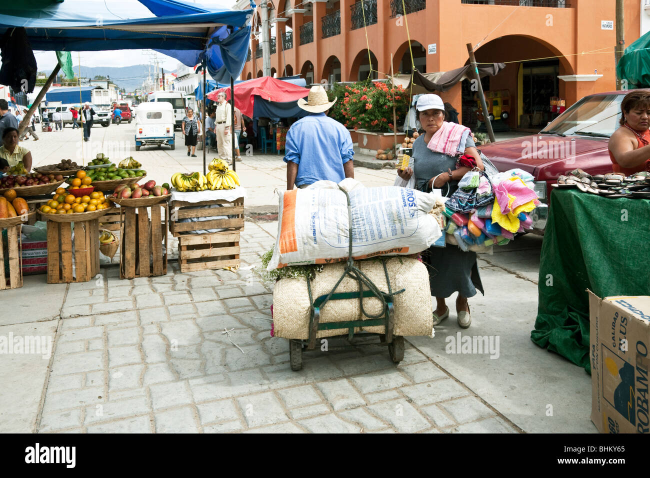 two heavily laden peddlers squeeze by each other at entrance to Ocotlan market Oaxaca State Mexico Stock Photo