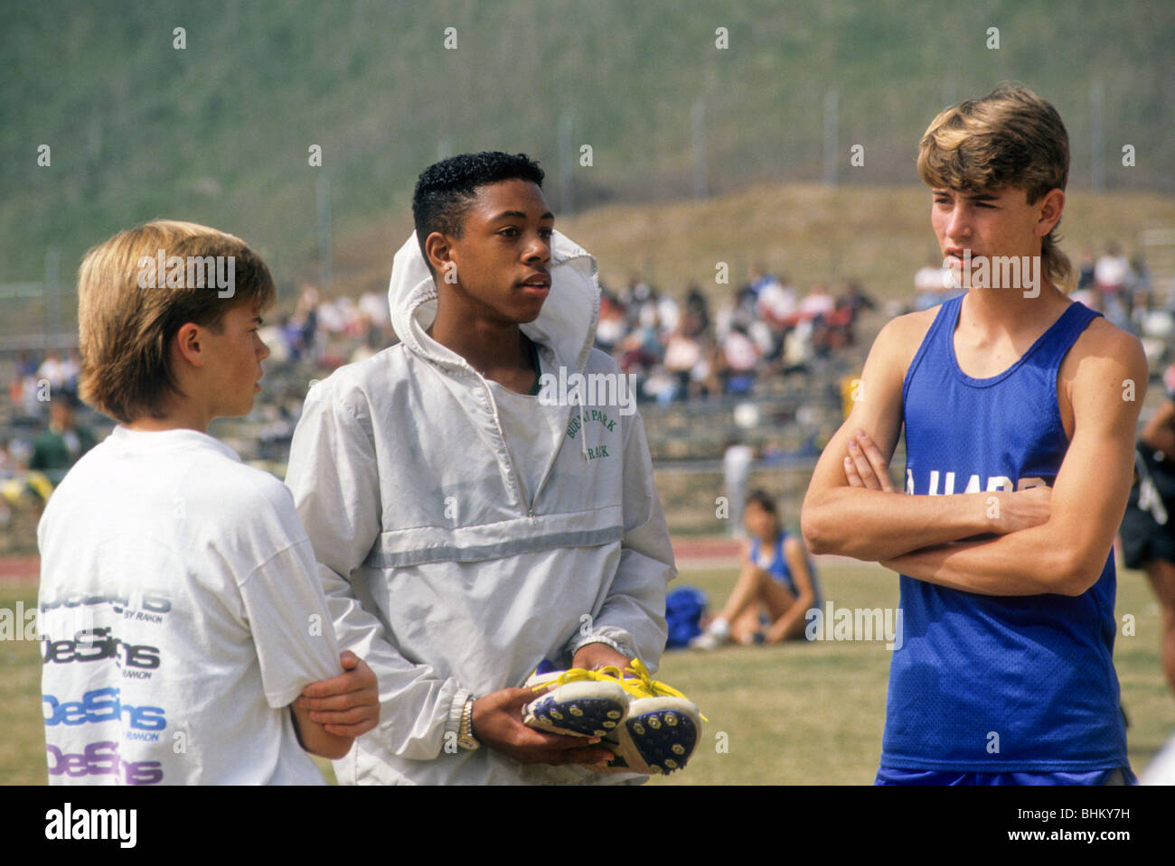 Three mixed race track teen runner boy male black white friend support share team member event sport Stock Photo