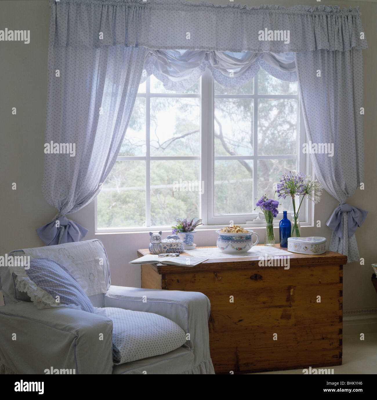 White Armchair And Pine Chest Of Drawers Below Window With Pale