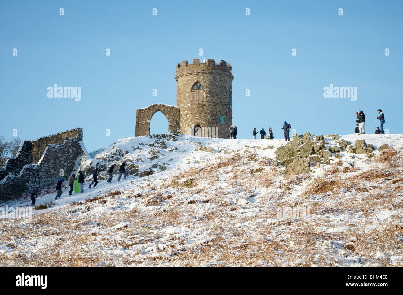 Snowy Winter Scene at Old John, Bradgate Park, Newtown Linford, Leicestershire. People having fun, sledging downhill. Stock Photo