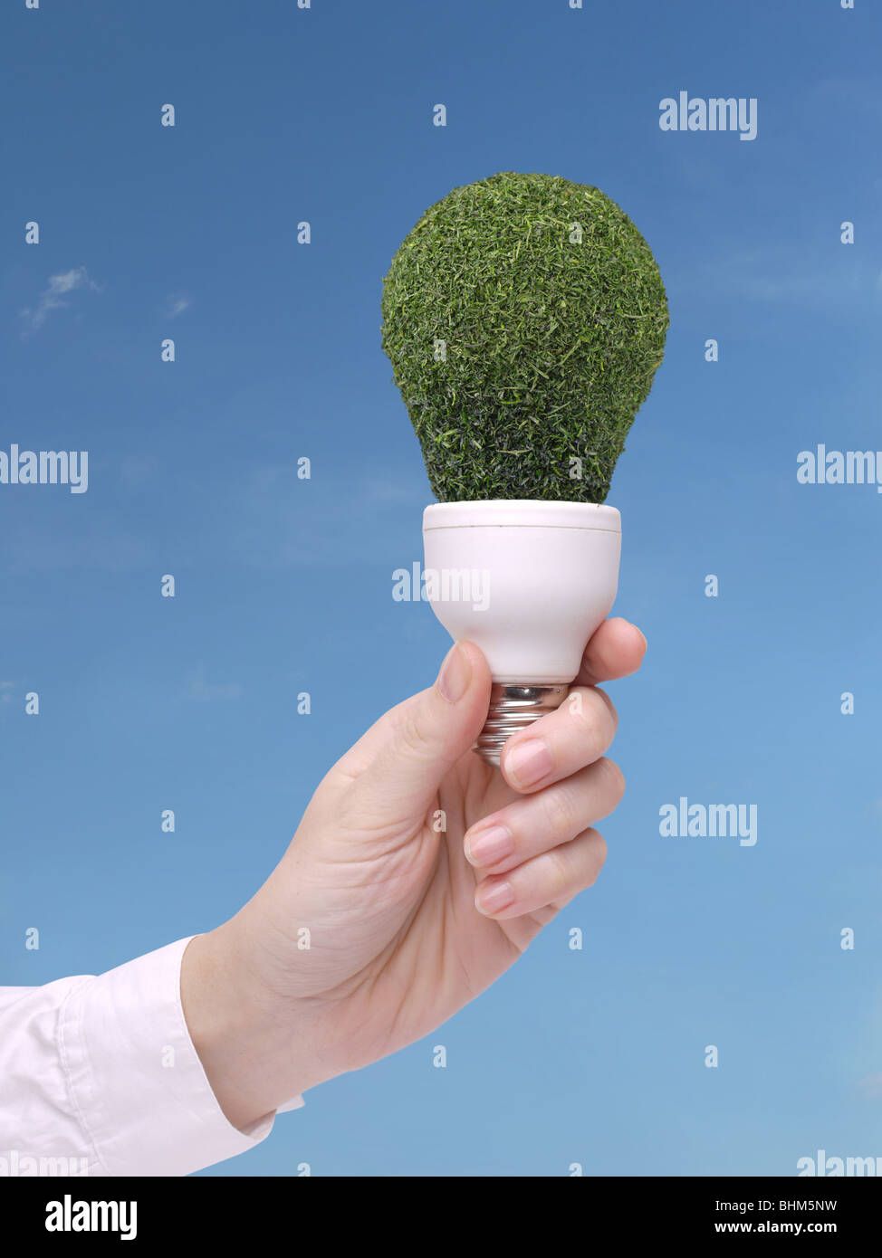 Female hand holding environmentally-friendly green bulb over blue sky - ecologic concept Stock Photo