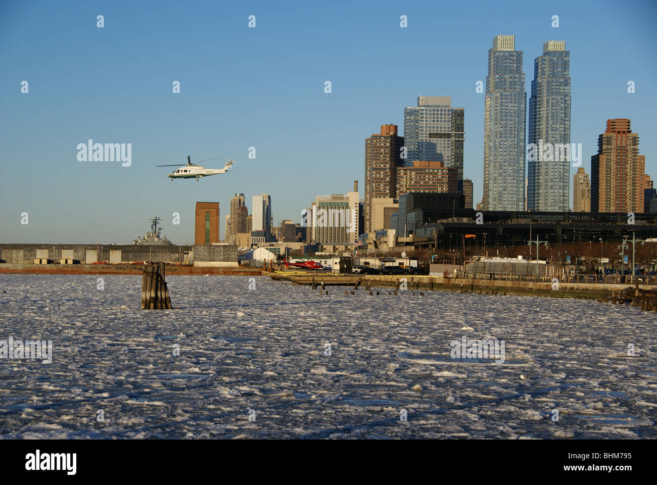 Helicopter takes off of a heliport near midtown Manhattan, right next to frozen and icy Hudson river Stock Photo