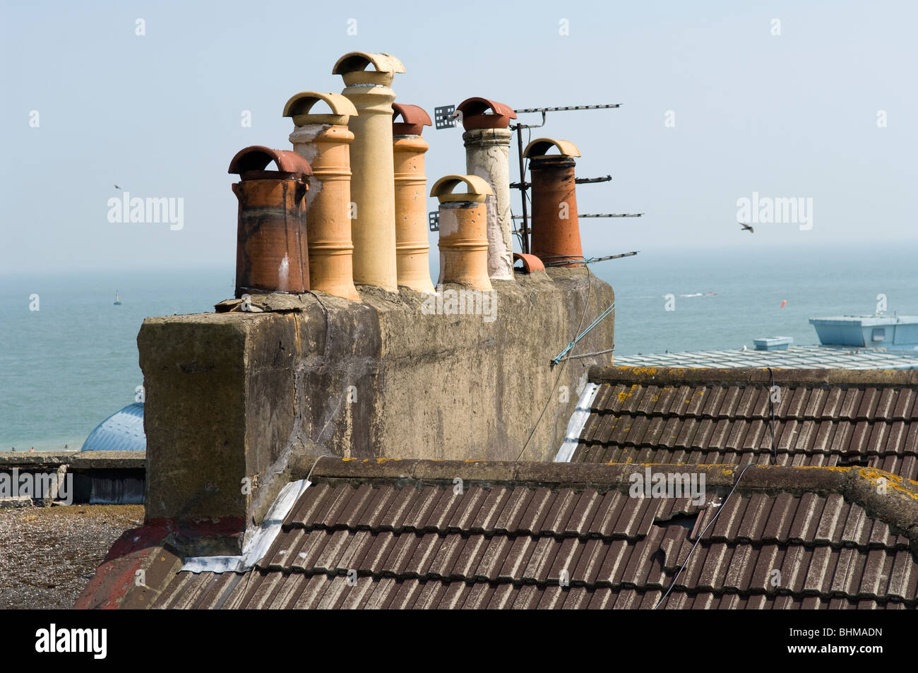Roof tops showing concrete interlocking tiles including broken tiles. Chimney stacks and pots and television aerials can be seen Stock Photo