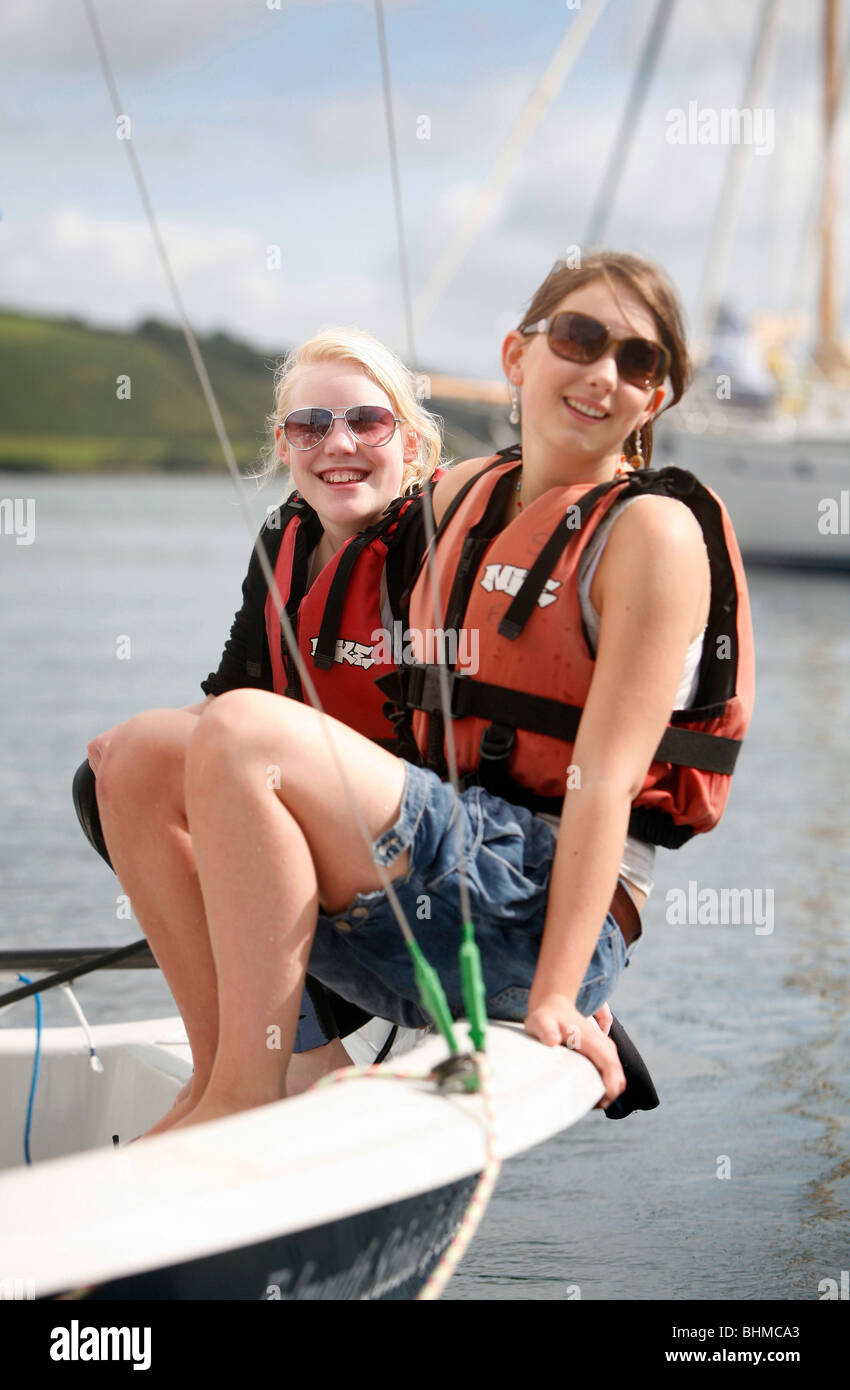 2 girls, wearing life jackets, on a sailing boat having fun and