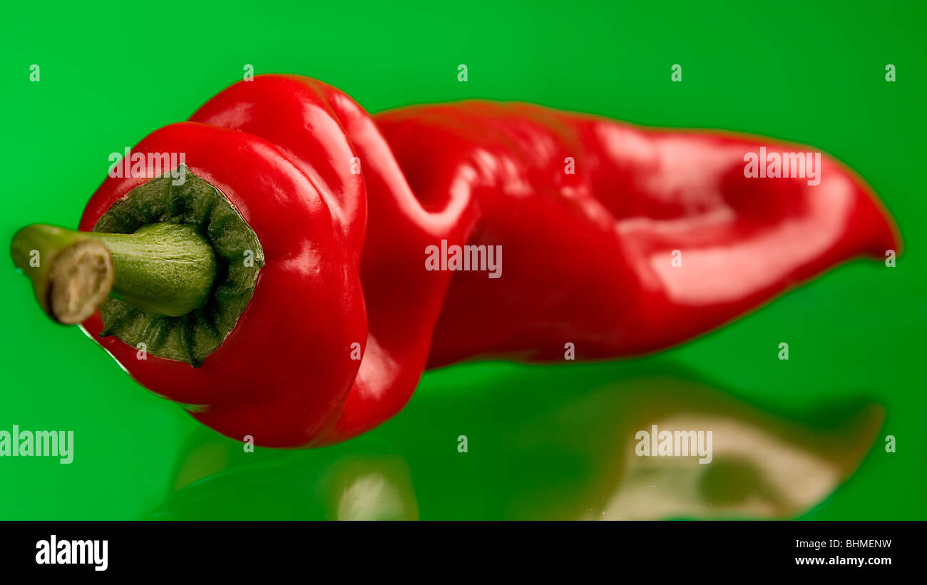 Crisp red chilli pepper against a vibrant green background. Stock Photo