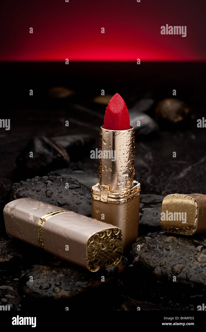 Red lipstick with water spray on rocks with a red glow background Stock Photo