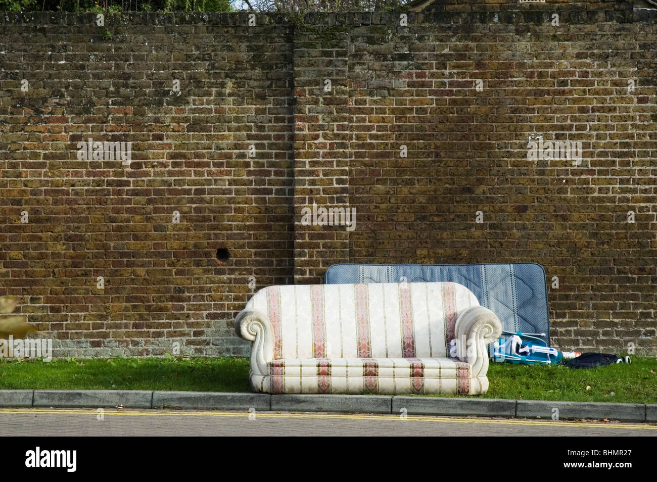 Fly-tipped rubbish beside a suburban road. Stock Photo