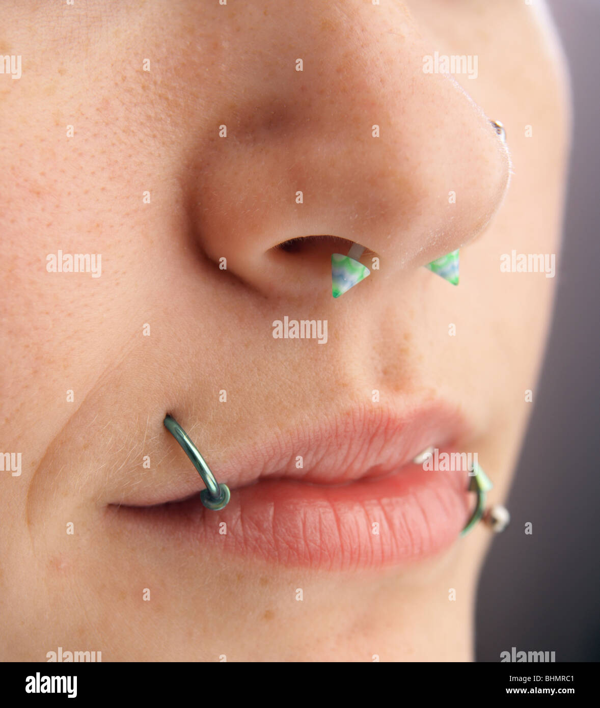 close up of a young womans face showing lip and nose piercings. Stock Photo