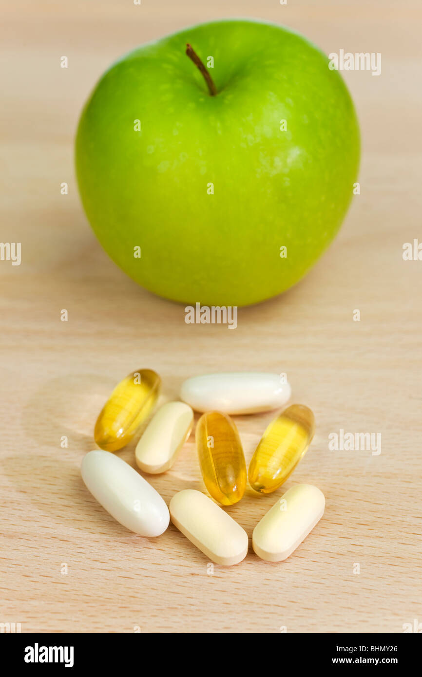 A green apple and tablets either medicinal pills or nutritional