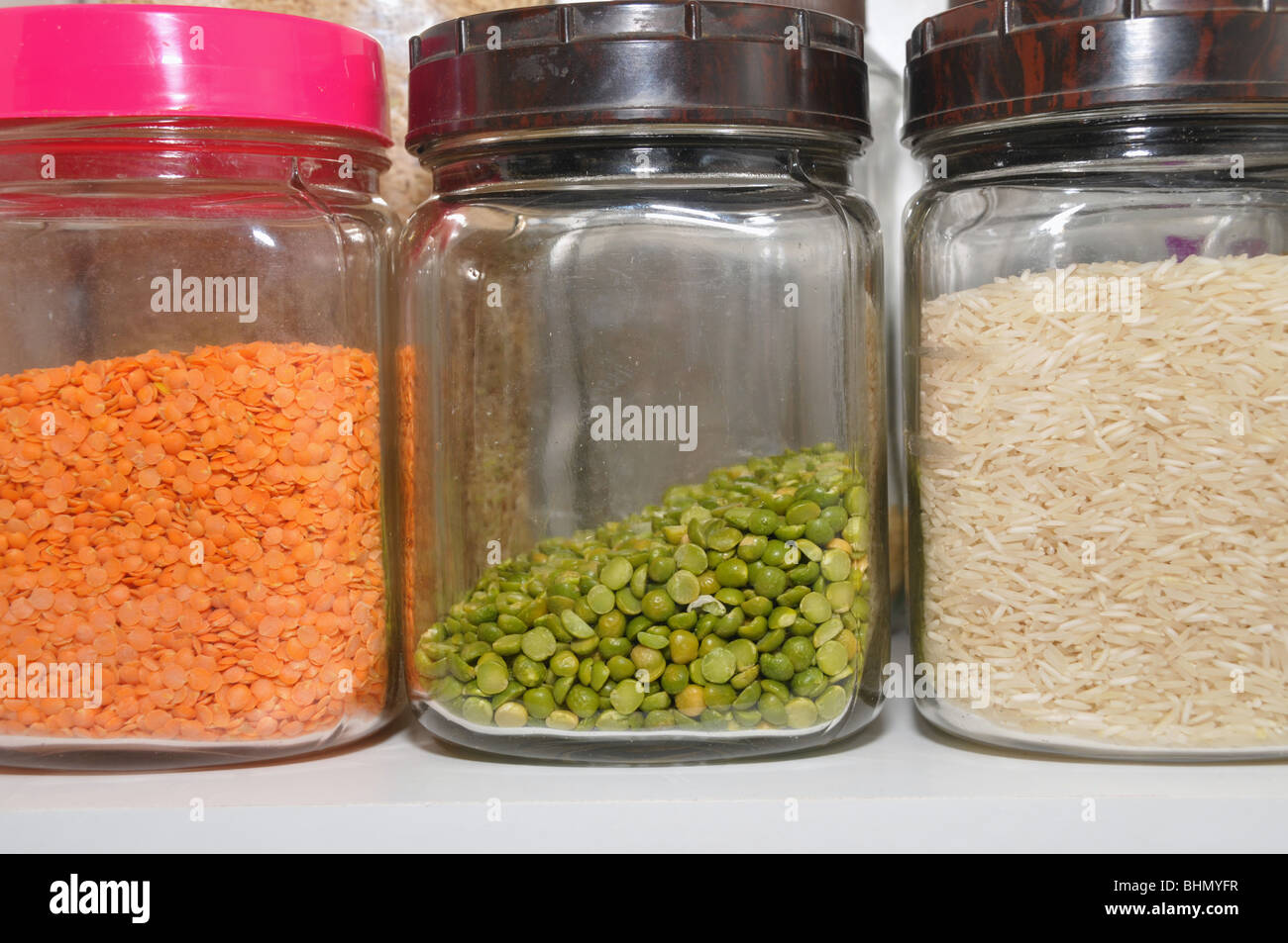 Three glass jars holding rice, and red and green lentils. Stock Photo