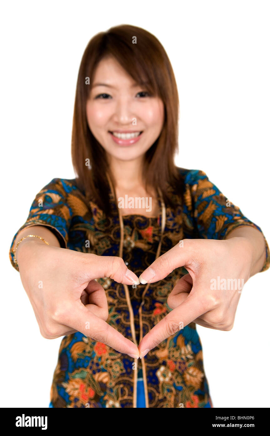 Malaysian girl wearing batik kebaya with hand forming a heart shape Stock Photo