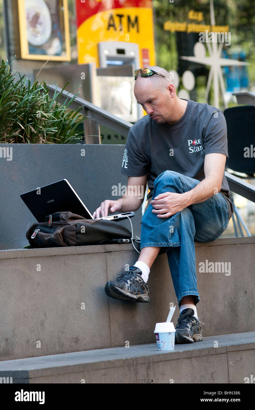 Man working on laptop outside in city street Stock Photo