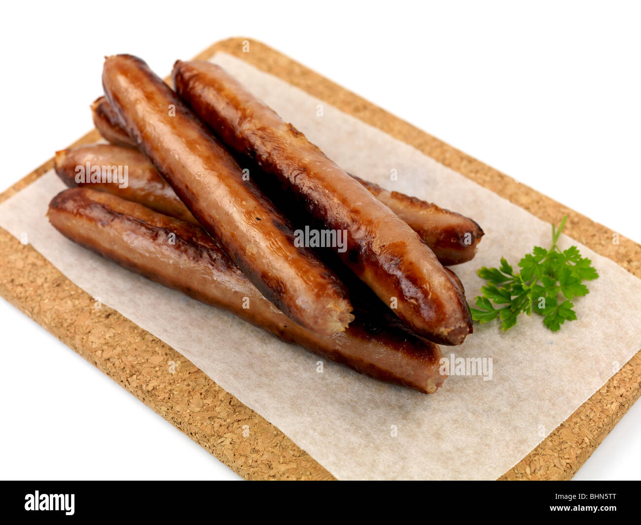 Cooked pork Sausages on a cork board isolated against a white