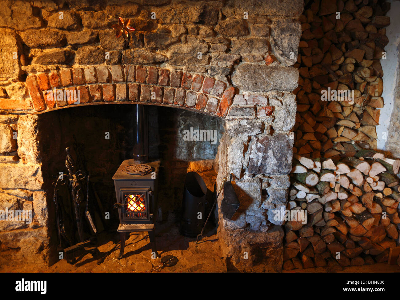 Traditional farmhouse fireplace with wood burner. Stock Photo