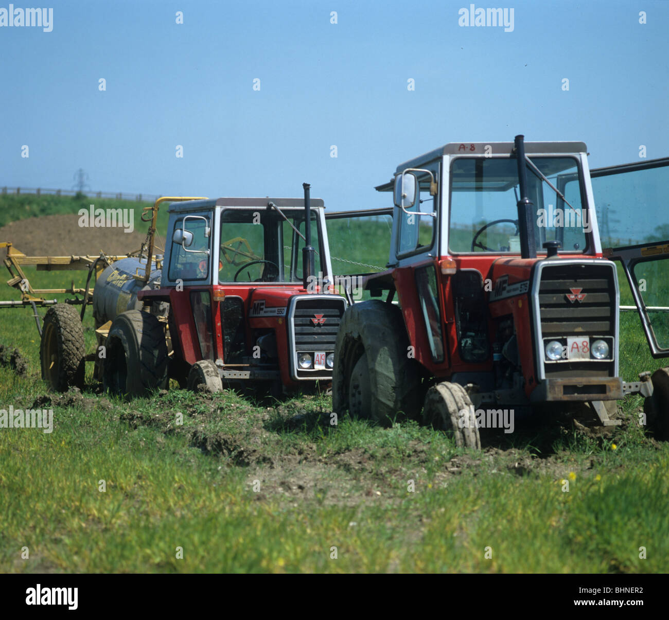 Two Massey Ferguson tractors bogged down in a field of young barley after heavy rain Stock Photo