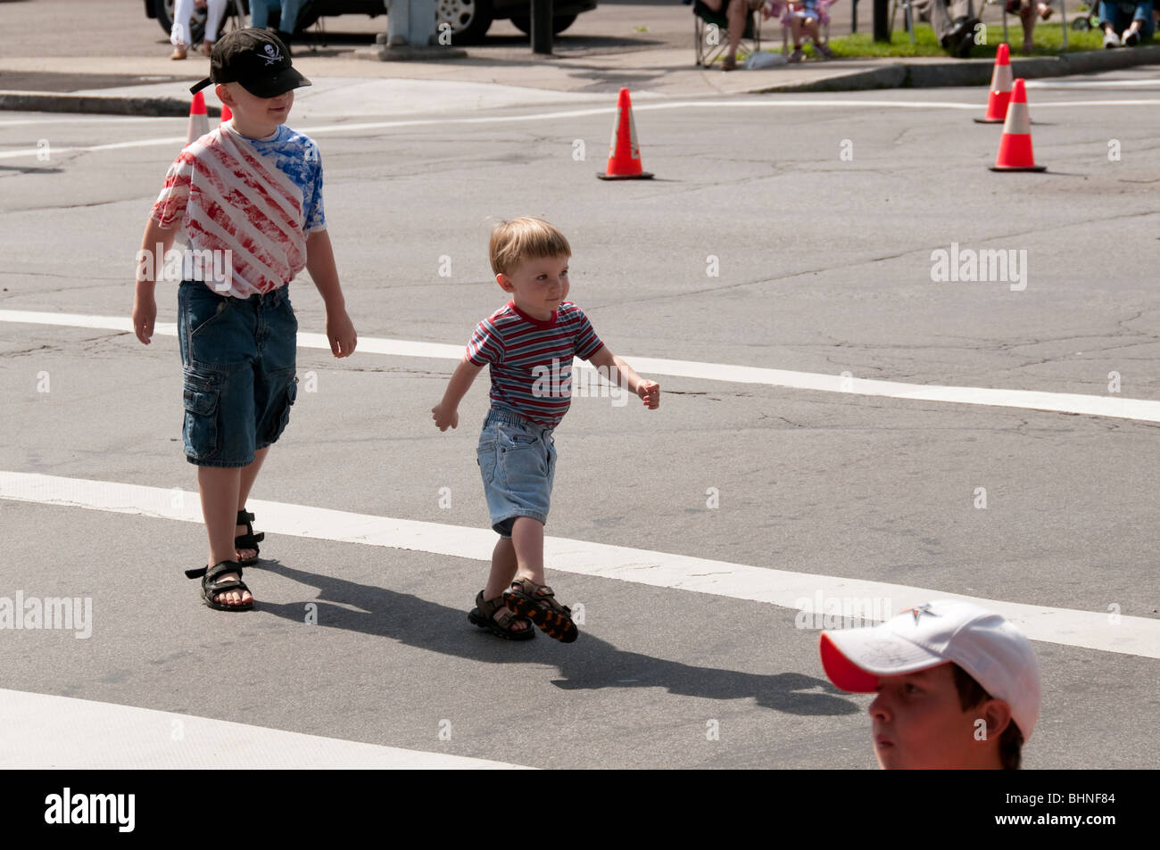 Boys crossing street, waiting for parade. Stock Photo