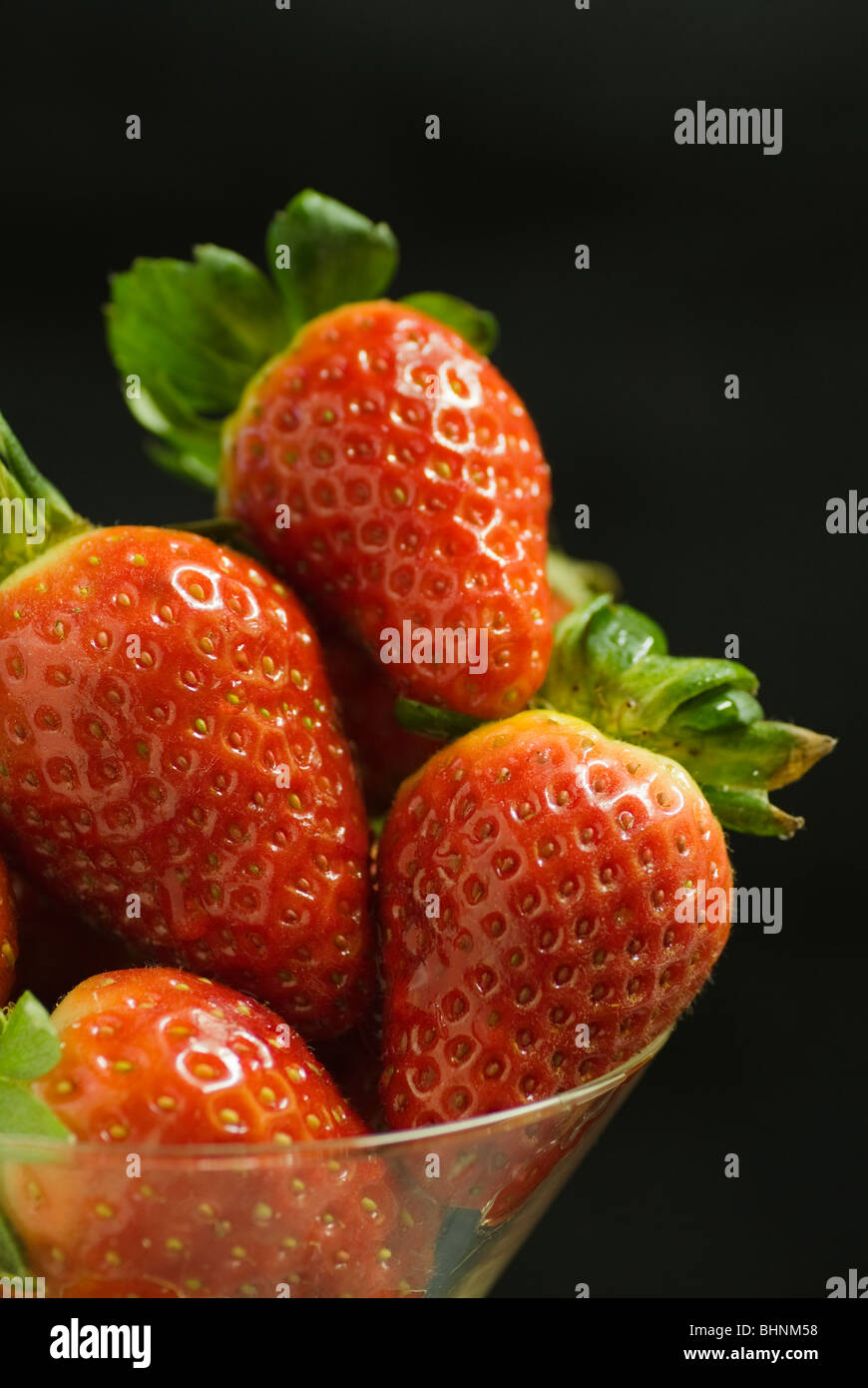 Strawberries in a glass bowl set against a black background Stock Photo ...