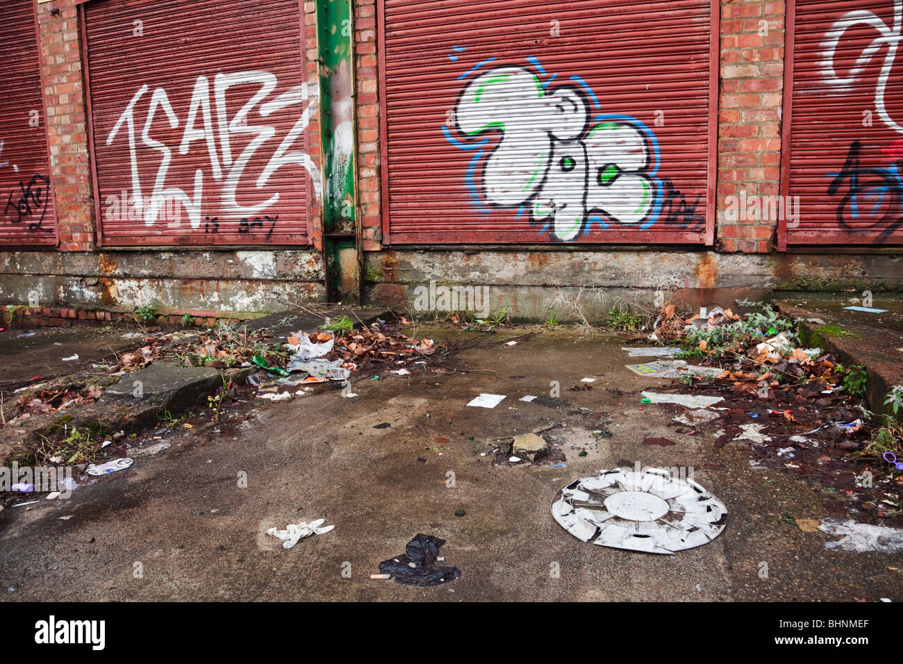 Graffiti on garage doors in urban street scene littered with dumped