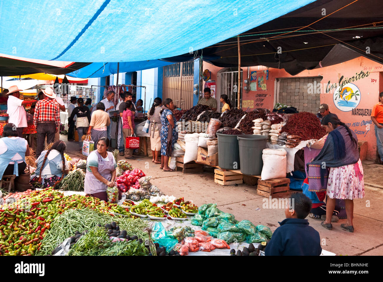 colorful awnings shade bountiful displays of fresh produce chili & spices as buyers & sellers crowd streets for Ocotlan market Stock Photo