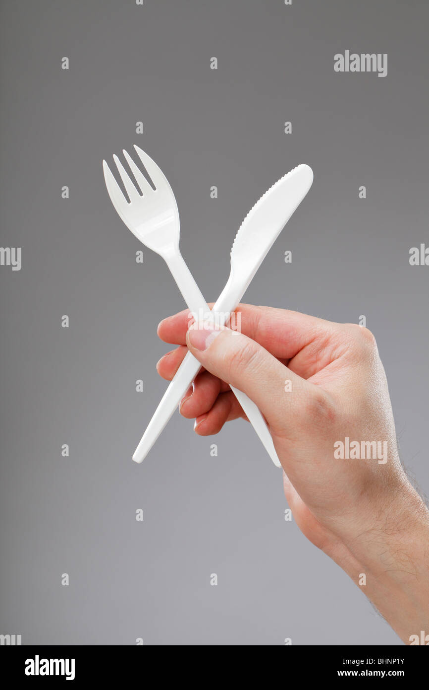 Hand holding white disposable plastic fork and knife Stock Photo Alamy
