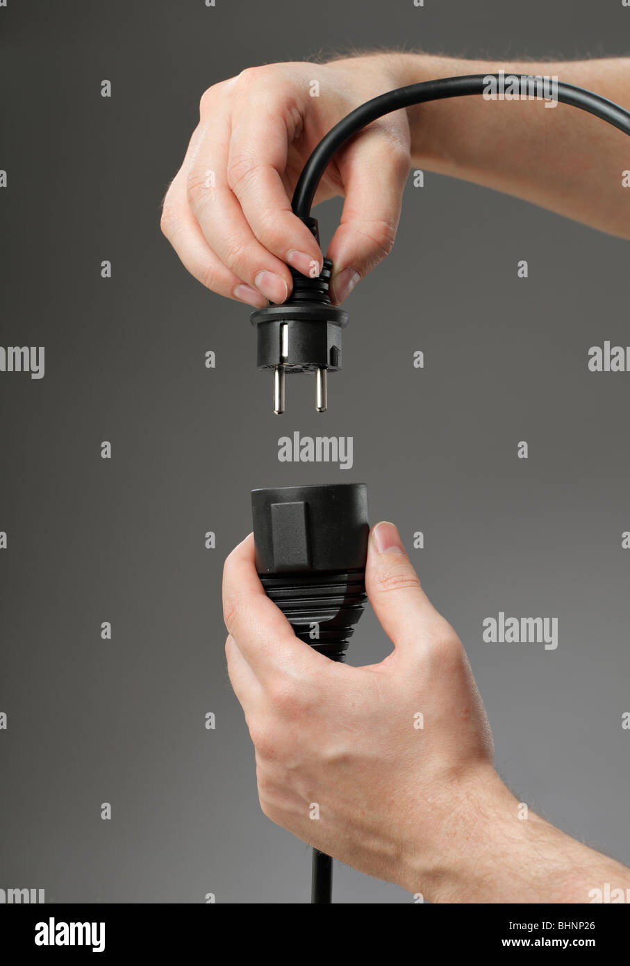 Hand plugging a black european extension cord Stock Photo Alamy