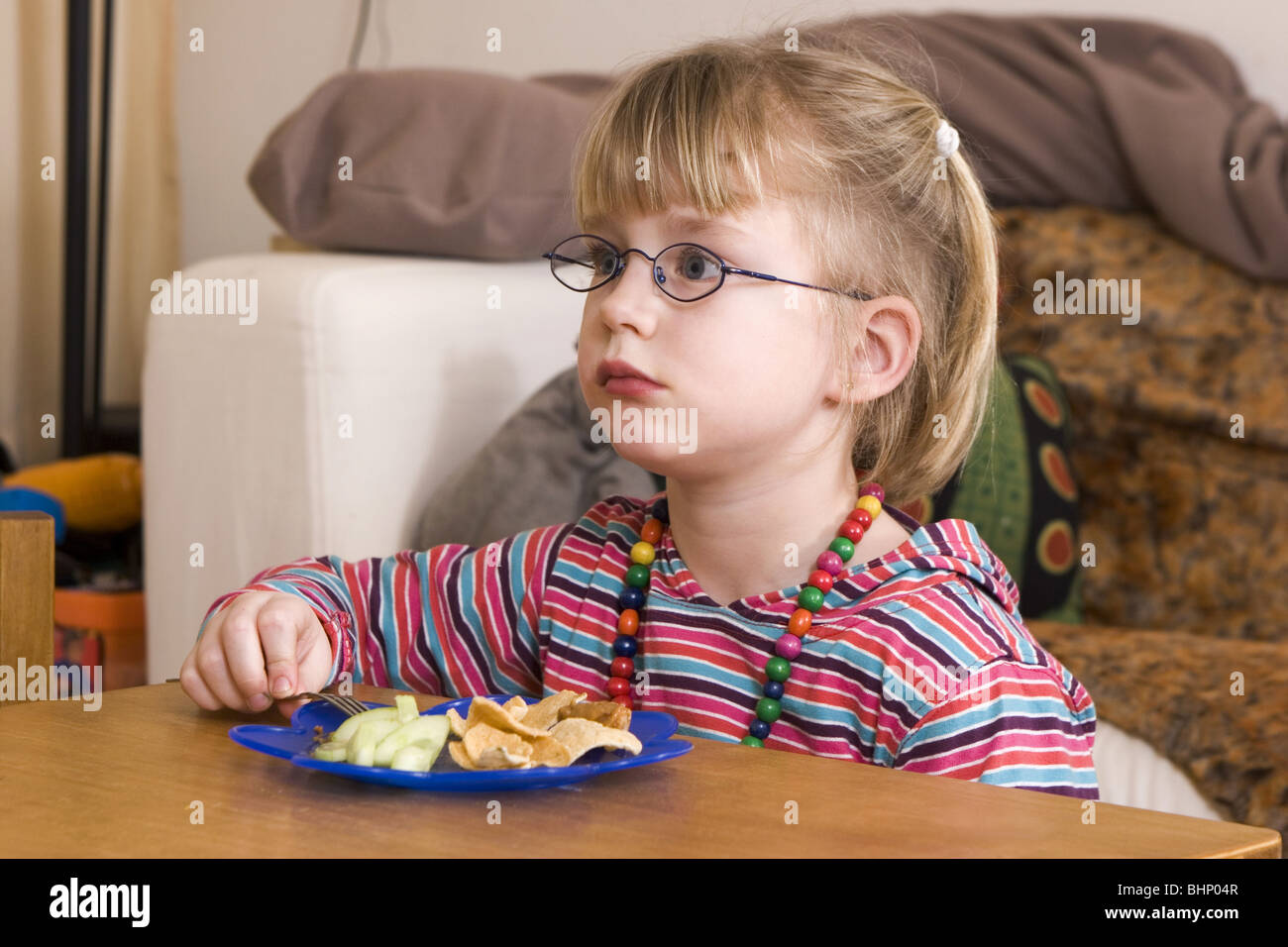 Young girl having family dinner alone while watching television and