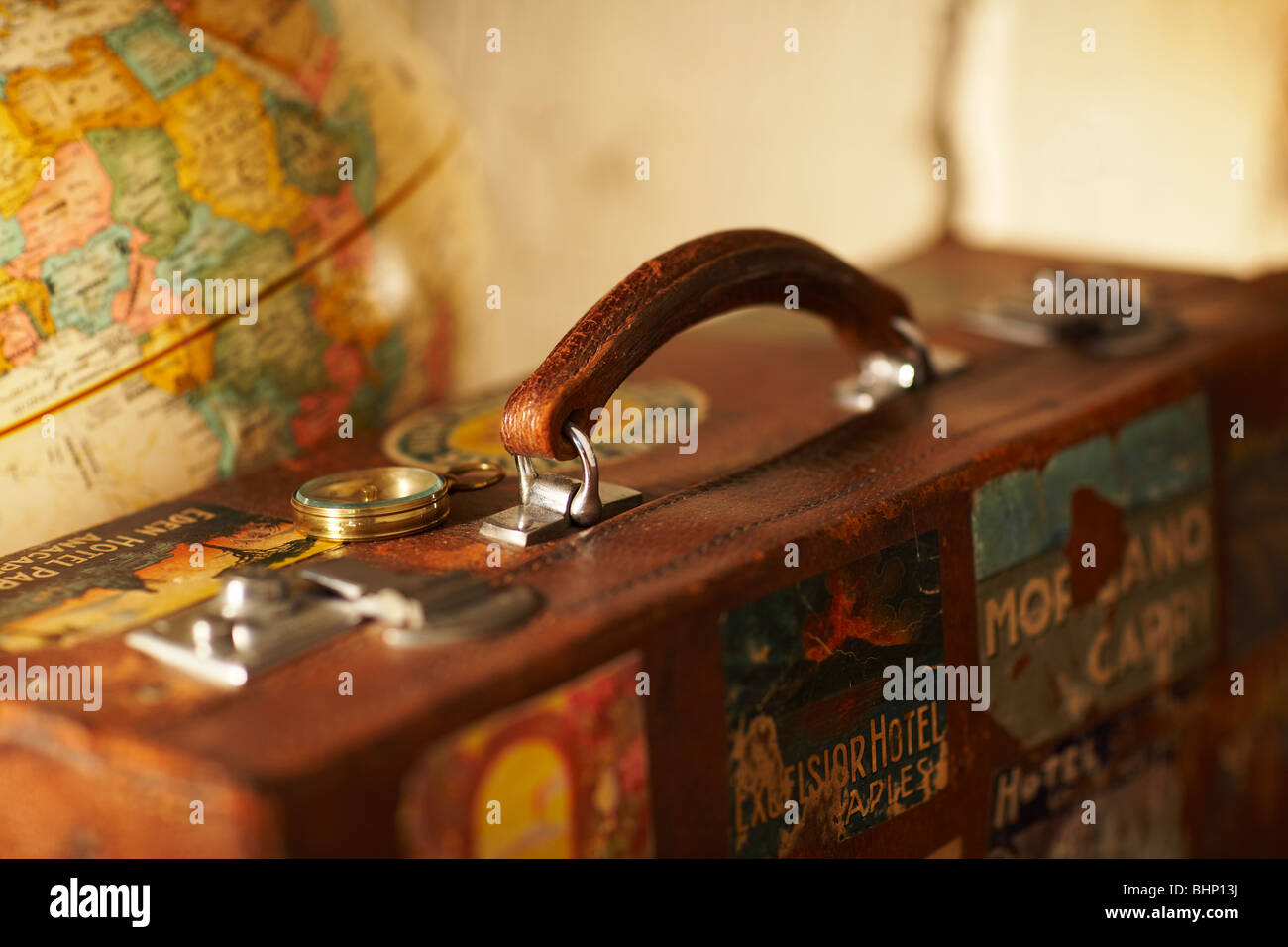 old labeled antique suitcase next to world globe Stock Photo
