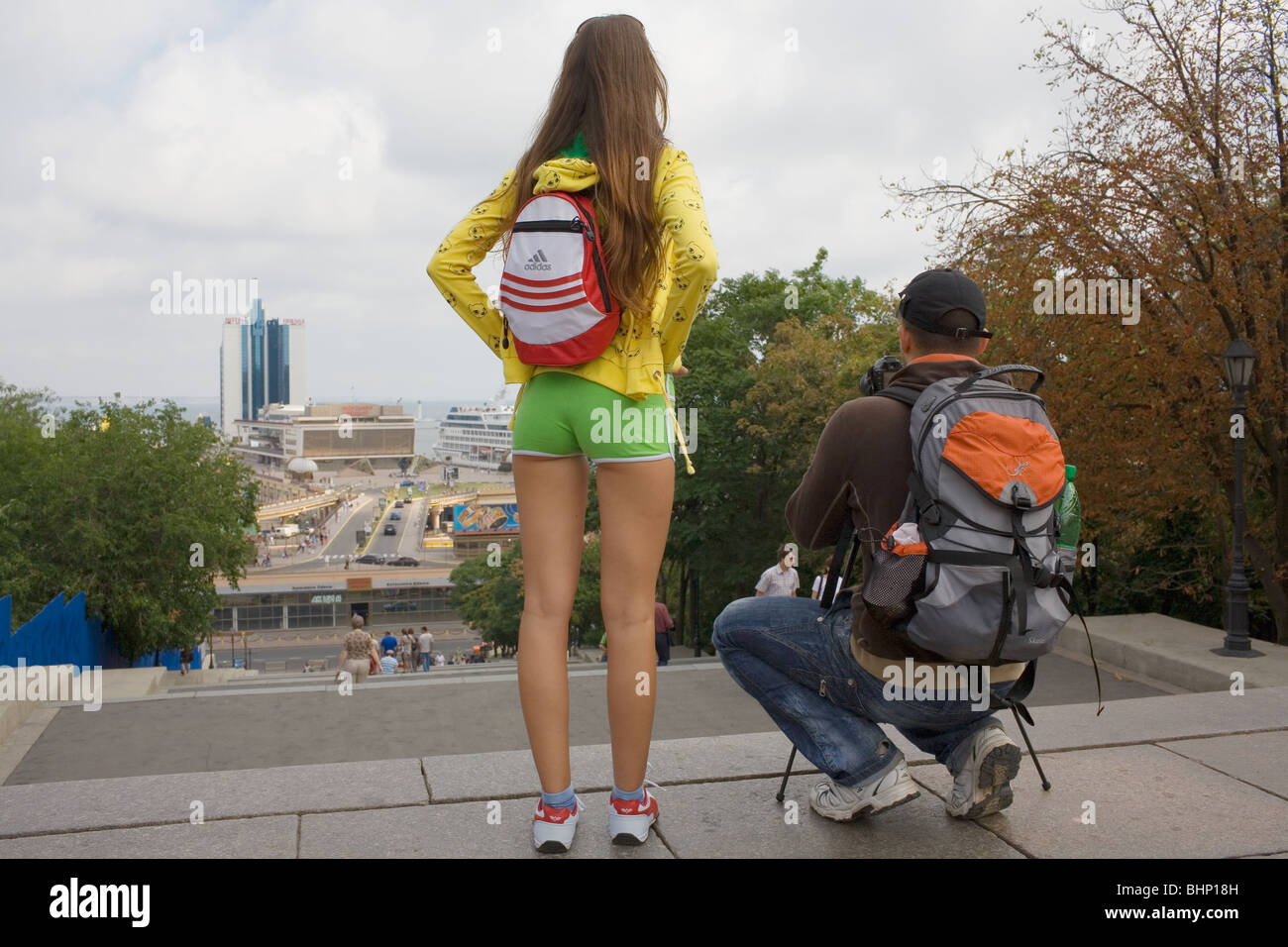 A girl in tight green shorts and yellow top stands with her boyfriend at the top of the Odessa steps in Southern Ukraine. Stock Photo