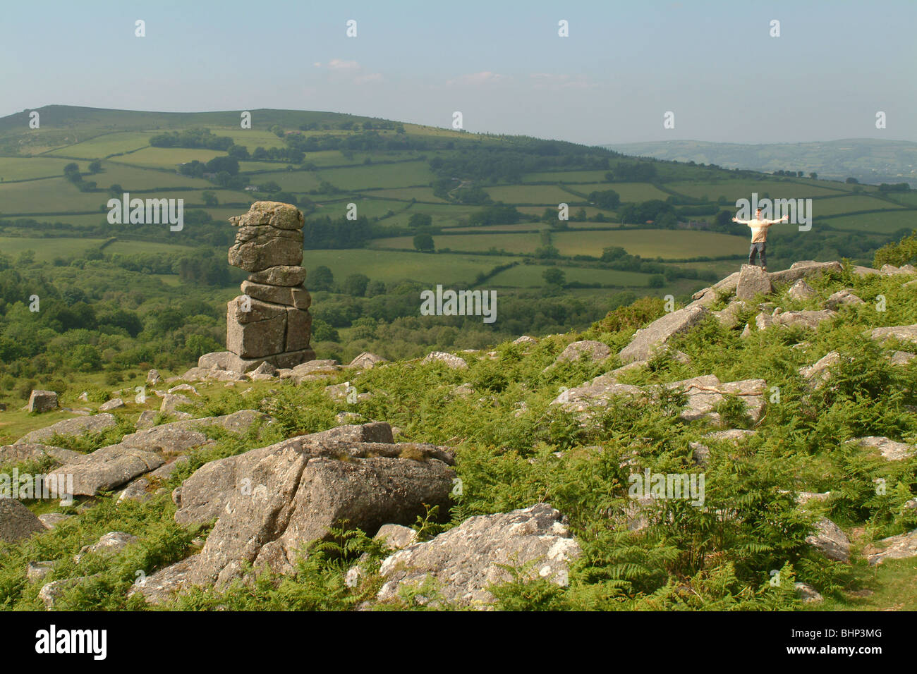 Hill walker at top of hill near stone monolith, Stock Photo