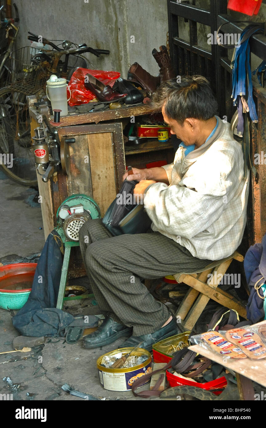 Chinese shoemaker fixing shoes in his street at Shanghai