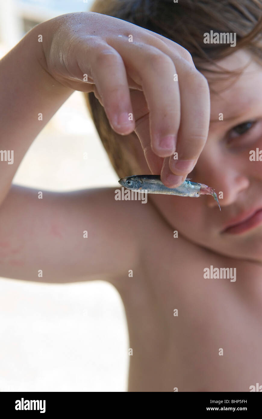 7 year old young boy bemoans the death of small fish by holding it up to camera Stock Photo