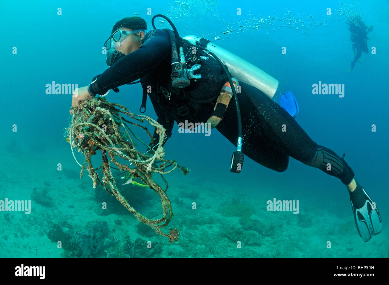 Reef gardener collecting old fishing lines and ropes from coral reef