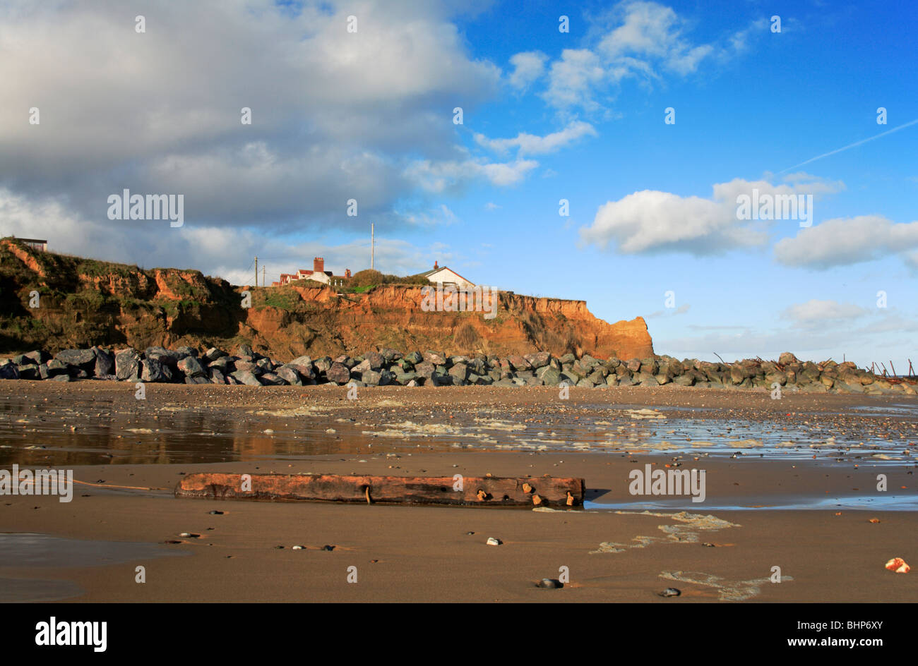 Old groyne post and rock armour protecting eroding cliffs on Happisburgh Beach, Norfolk, United Kingdom. Stock Photo