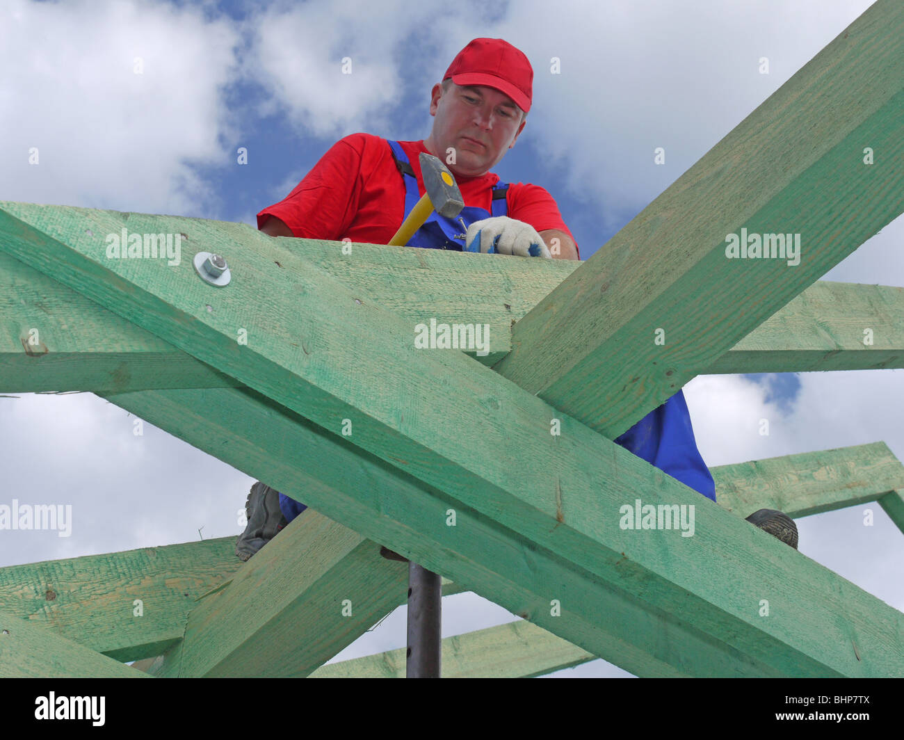 Carpenter driving a nail into house rafter framing beam Stock Photo