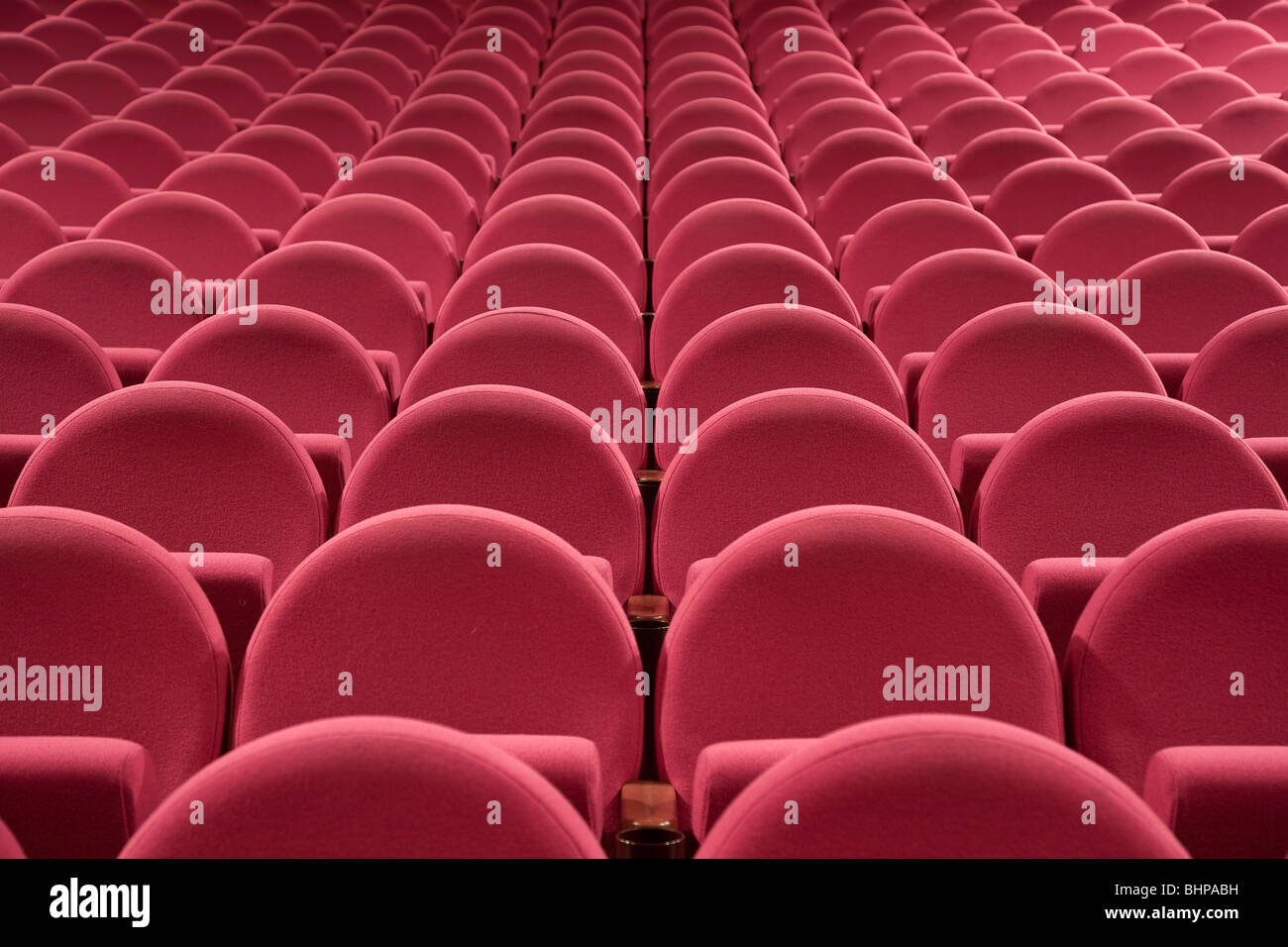 Close-up of empty cinema auditorium with line of pink chairs. Stock Photo