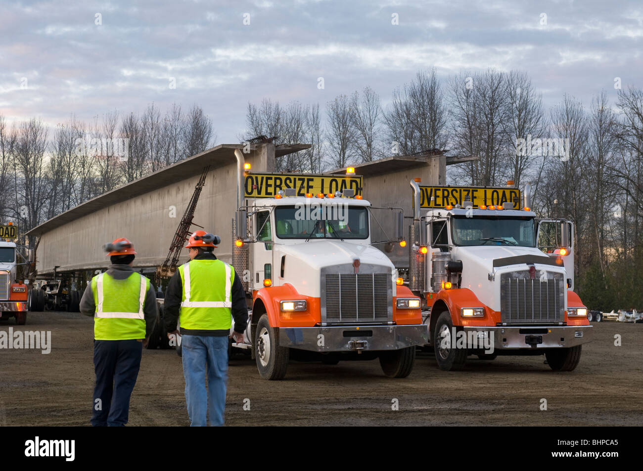 two bridge construction workers walking toward two truck trucks holding
