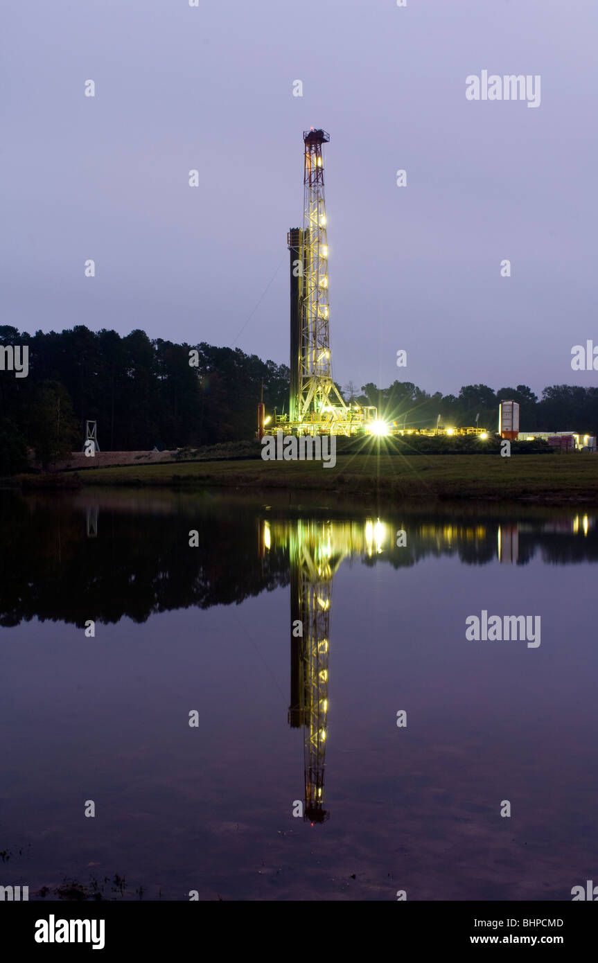Oil drilling rig at night with water reflection in foreground Stock Photo