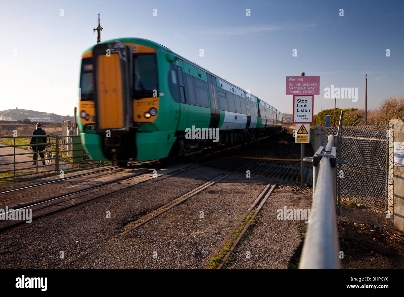 A passenger train passing over Tide Mill Manually Operated Level Crossing in Sussex. Stock Photo