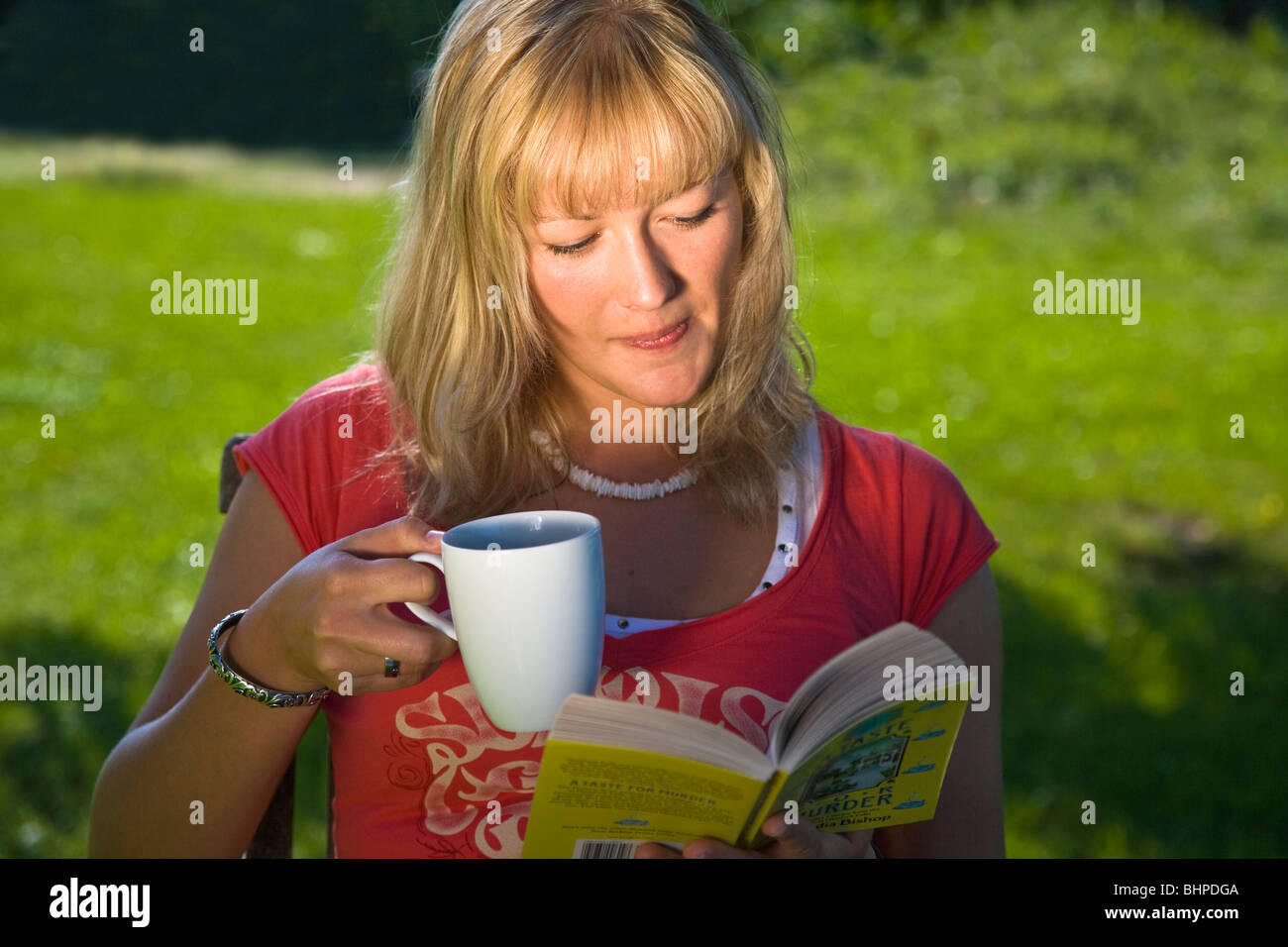 Young woman reading a book in the garden Stock Photo