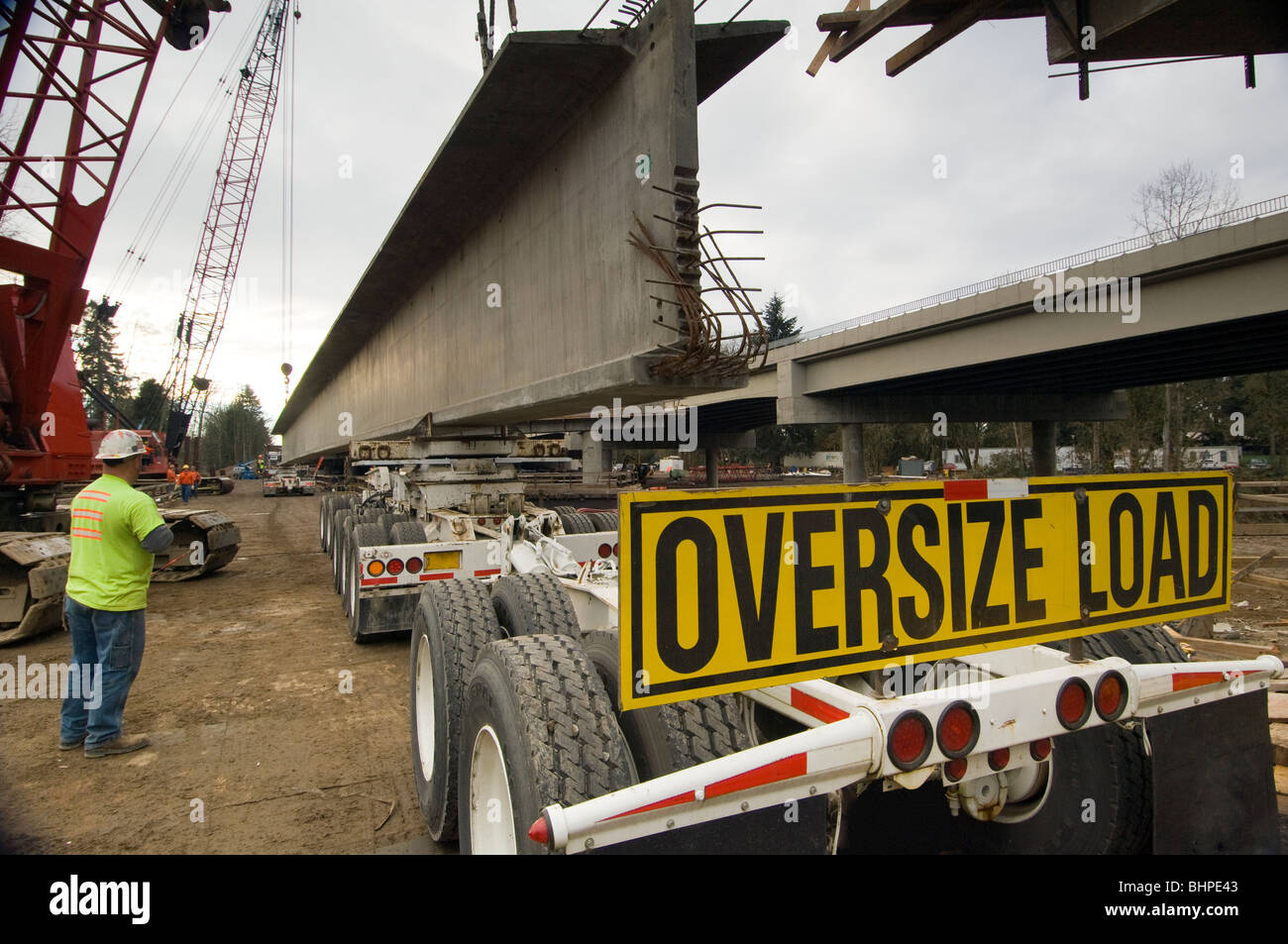 Bridge construction worker overseeing steel truss being lifted off a ...